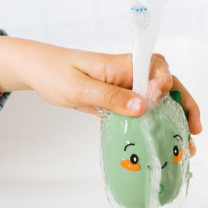 Dinosaurier-Schallzahnbürste in der Hand unter dem Wasserstrahl