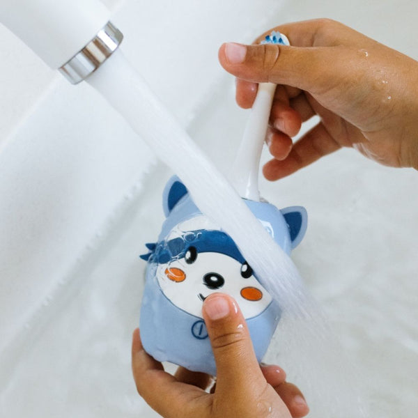 Waschbär-Schallzahnbürste in der Hand unter fließendem Wasser