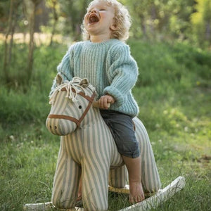 Kind reitet auf dem Schaukelpferd Sam AIDEN im Garten