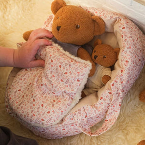 Kinderhand legt Gabin und einen großen Bären in einen Stoffschlafsack