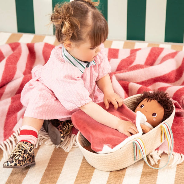 Mädchen legt eine Puppe in den Puppentragekorb von Lilliputiens