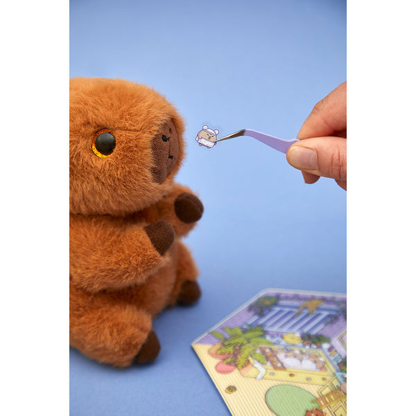 Pinzette hält einen Mini-Sticker vor einer Wohnszene