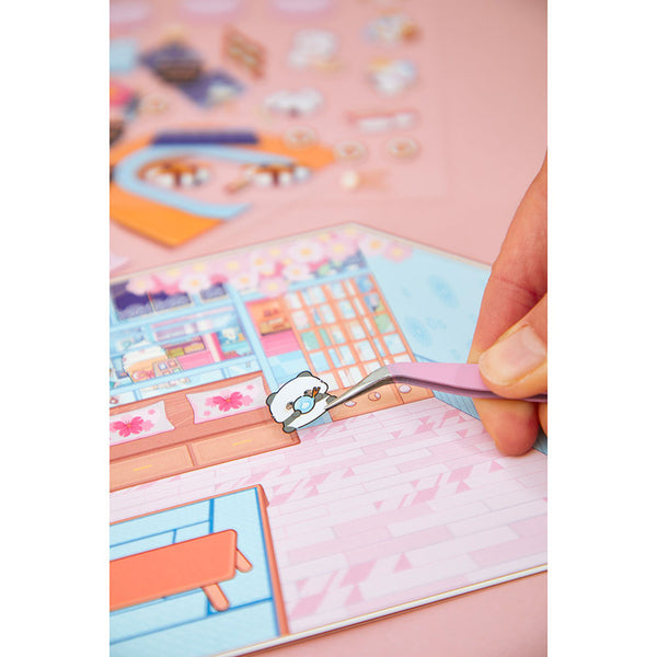 Hand setzt mit der Pinzette einen Mini-Sticker in die Szene