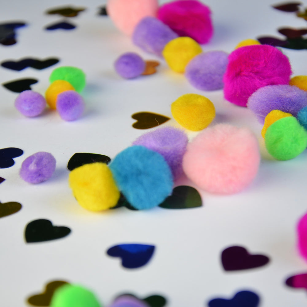 Bunte Bastelmaterialien von Apli Kids mit Pompons und herzförmigen Glitzerstücken für kreative Projekte