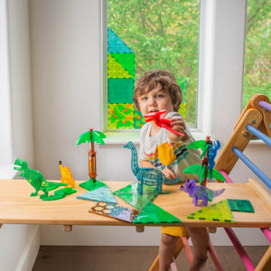 Kind spielt mit Magnetbausteine Dino World XL und erstellt Dinosaurier-Kreationen am Tisch