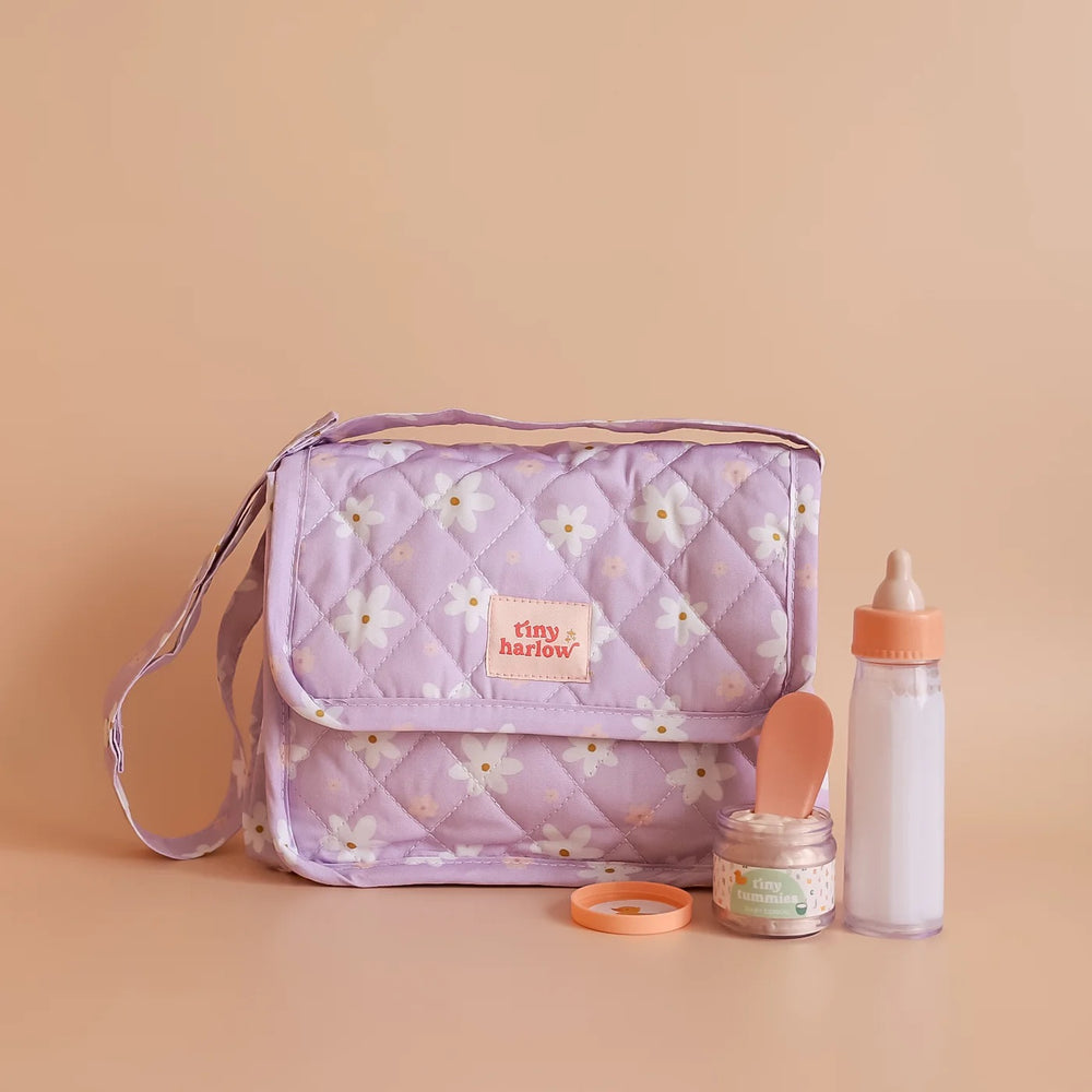 Tasche mit Zubehör für Puppen von Tiny Harlow, lila mit Blumenmuster, inklusive Flasche und Löffel.